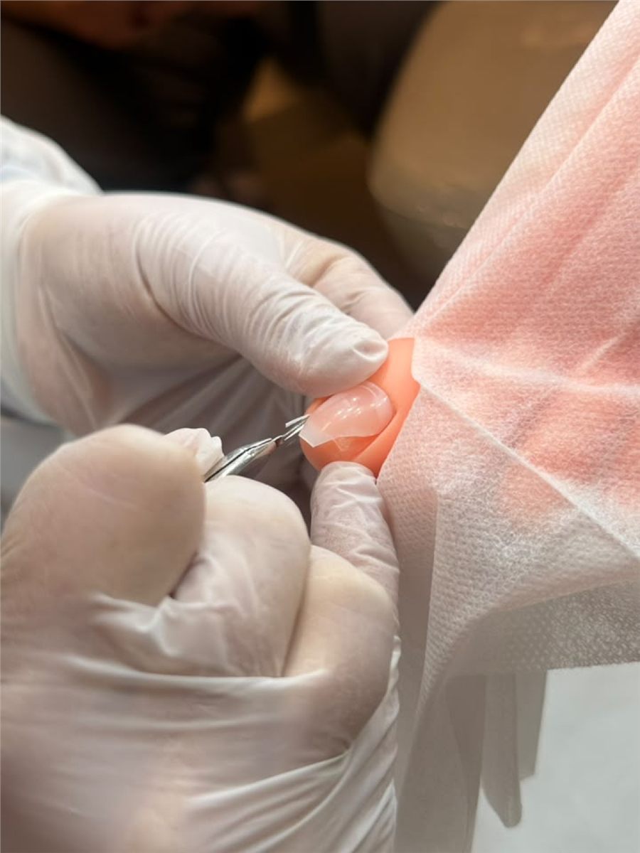 Detalhe do atendimento, instrumento trabalhando na lateral da unha